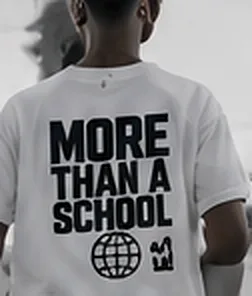 White tee with the graphic MORE THAN A SCHOOL.