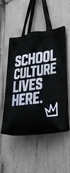 Black tote bag printed with SCHOOL CULTURE LIVES HERE and a crown mark.
